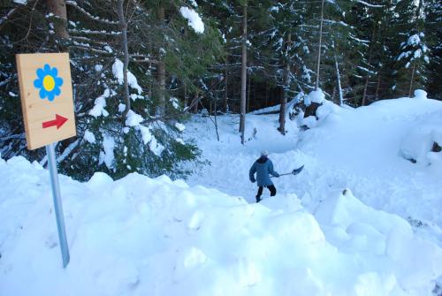 a person walking through a pile of snow next to a sign at Country House & Spa in Mislinja