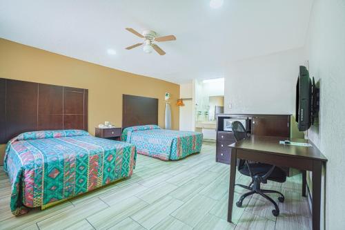 a hotel room with two beds and a desk at Texas Inn San Benito near Harlingen in San Benito