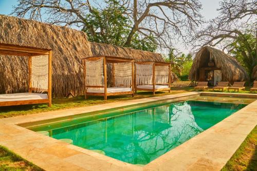 a resort with a swimming pool and a thatch roof at Hotel Isla Mucura in Isla Mucura