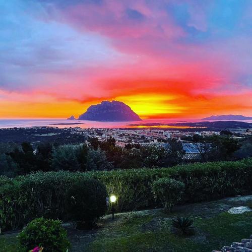 a sunset over a city with a mountain in the distance at Villa Acchiappasogni in Porto San Paolo