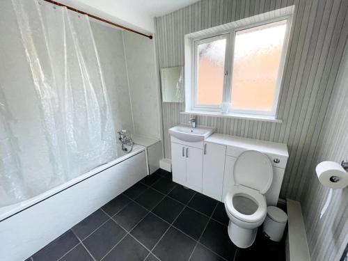 baño con aseo, bañera y ventana en 5-Bedroom Cottage in Healing, Grimsby en Healing
