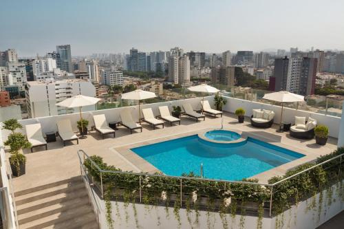 uma piscina no telhado de um edifício com cadeiras e guarda-sóis em Costa del Sol Wyndham Lima City em Lima