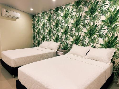 two beds in a room with a tropical wallpaper at Oasis Hotel in San Andrés