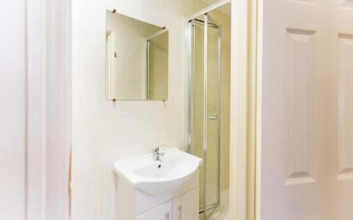 uma casa de banho branca com um lavatório e um espelho em Litsa's Central Studios em Londres
