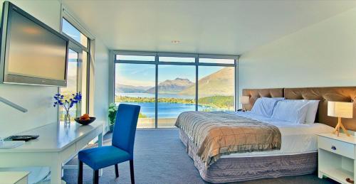 a bedroom with a large bed and a desk and a deskablish at Spectacular Panoramic 5Bedroom Lakeview in Queenstown