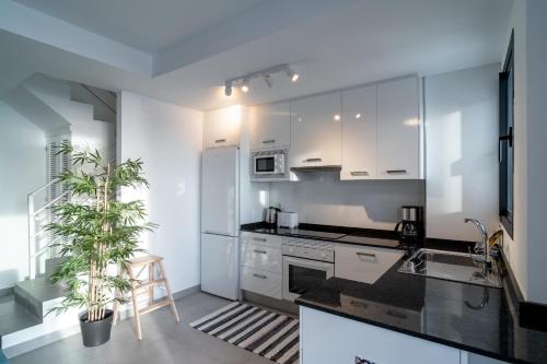 a kitchen with white cabinets and black counter tops at Terrazas de Ladera Duplex 7 Casasol in Nerja