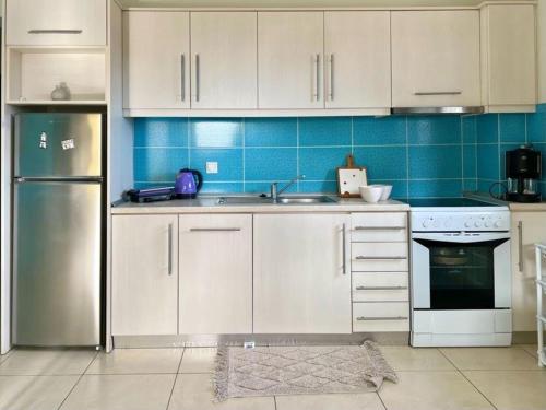 a kitchen with white cabinets and a stainless steel refrigerator at Sermilie Beach Houses in Psakoudia