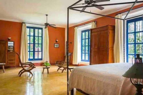 um quarto com paredes cor de laranja, uma cama e janelas em Hacienda extraordinaria, jardines preciosos y pirámides 