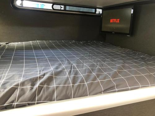 Una cama vacía en una habitación con un reloj. en Barco KMP en Barcelona