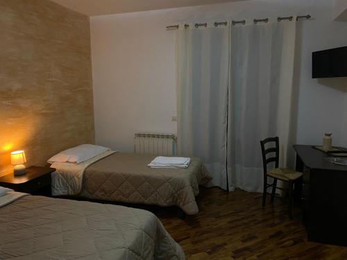 ein Hotelzimmer mit 2 Betten, einem Tisch und einem Schreibtisch in der Unterkunft B&B Spanò in Polistena