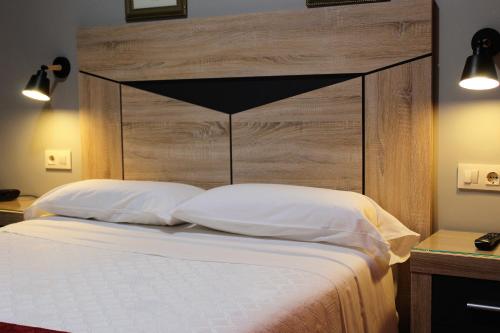 a bed with a large wooden headboard and white pillows at Hostal Madrid in Toledo