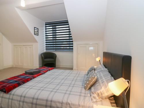 a bedroom with a bed with a plaid blanket and a window at RockStar Cottage in Macduff