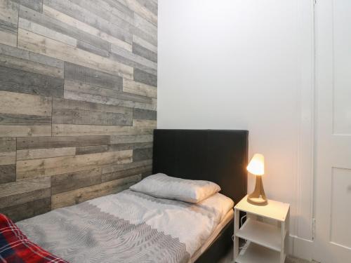 a bedroom with a wooden accent wall with a bed at RockStar Cottage in Macduff