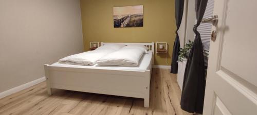 Una cama pequeña con sábanas blancas y almohadas. en Nordseezimmer - WLAN, Parkplatz, eigenes Bad, Fahrradschuppen, elektrischer Rollladen, en Otterndorf