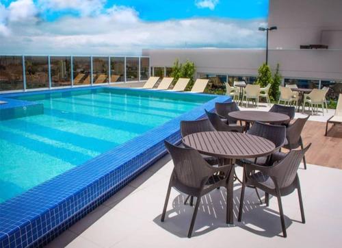 una piscina en la azotea de un edificio con mesas y sillas en FLAT 22º andar totalmente mobiliado lazer completo, en Guarulhos