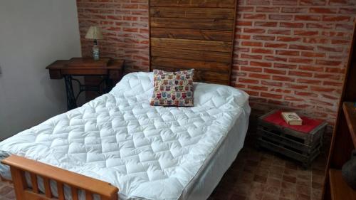 Cama grande en habitación con pared de ladrillo en La Casita en Santa Clara del Mar