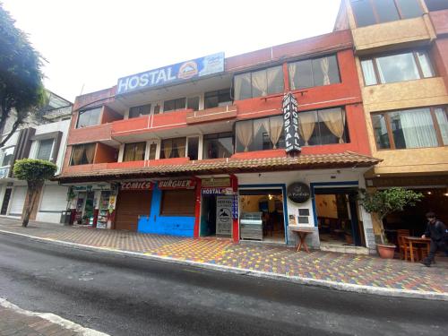 un edificio sul lato di una strada con un ombrello di Hostal los Andes a Baños