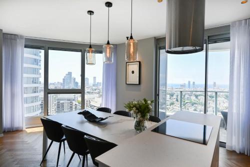 a dining room with a white table and chairs and large windows at Silk & Silver by HolyGuest in Tel Aviv