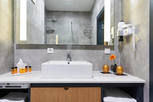 a bathroom with a white sink and a mirror at WENS Hotel in Mainz