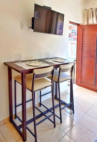 a kitchen with a table with chairs and a television at Vacacional Azueta - Departamento a unos pasos de la playa in Mazatlán