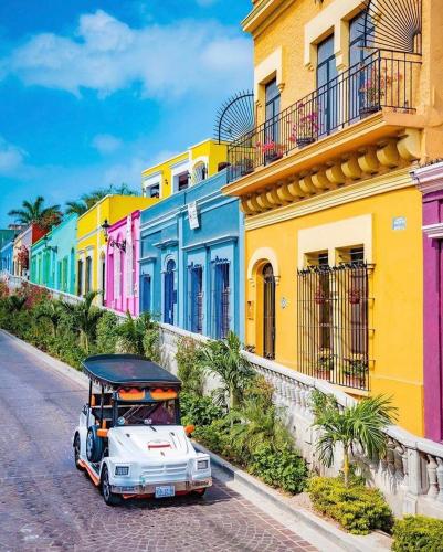 a car driving down a street with colorful houses at Vacacional Azueta - Departamento a unos pasos de la playa in Mazatlán
