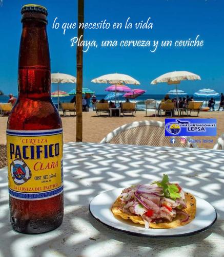 a bottle of beer sitting on a table with a plate of food at Vacacional Azueta - Departamento a unos pasos de la playa in Mazatlán