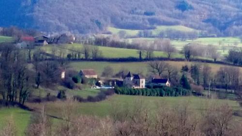 a house in a green field with trees and hills at Hotel La Bastie d'Urfé in Naussac