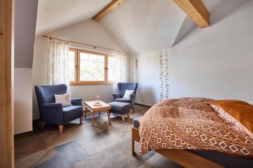 ein Schlafzimmer mit 2 Stühlen, einem Bett und einem Tisch in der Unterkunft Biopension Satya in Offenburg