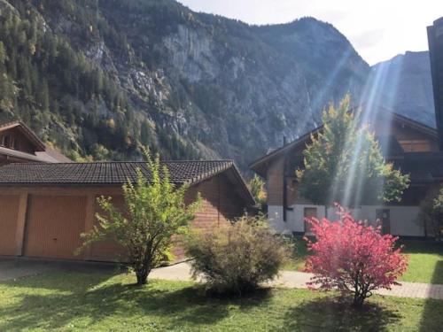 a house with trees and mountains in the background at Komfortabel, Perfekte Lage, neue Wohnung, gratis P in Lauterbrunnen