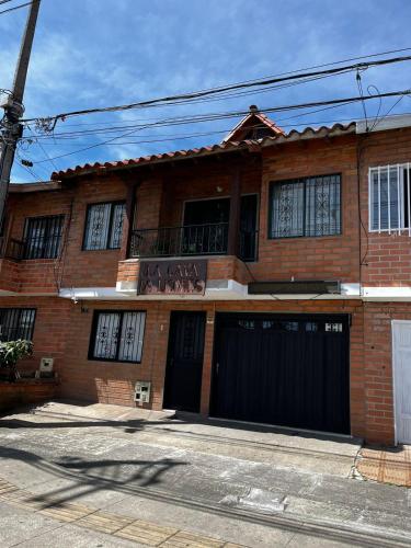 a brick house with two garage doors and a balcony at Letto Hostal in Rionegro