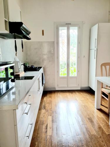 une cuisine avec des armoires blanches et un plancher en bois dans l'établissement Villa La Closeraie, à Amélie-les-Bains-Palalda