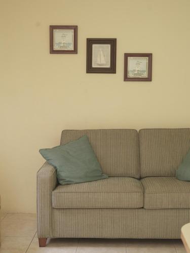 a couch sitting in a living room with two pictures on the wall at Aruba Tropic Apartments in Noord