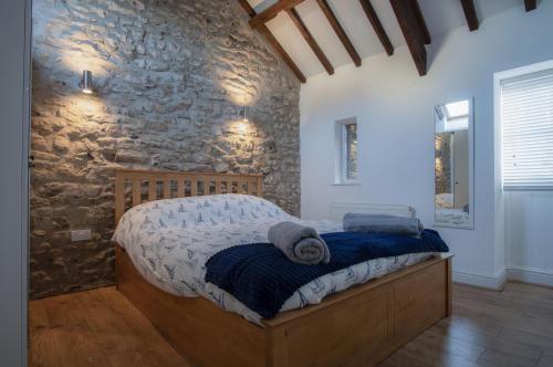 a bedroom with a bed with a stone wall at The Old Stables - 3 Bedroom Cottage - Angle in Angle