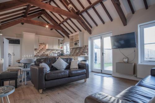 a living room with a leather couch and a table at The Old Stables - 3 Bedroom Cottage - Angle in Angle