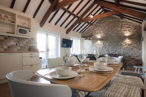 a dining room with a wooden table with chairs and a kitchen at The Old Stables - 3 Bedroom Cottage - Angle in Angle