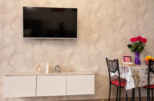 un soggiorno con armadio bianco e TV a parete di Апартаменты с этническими мотивами с видом на горы a Almaty