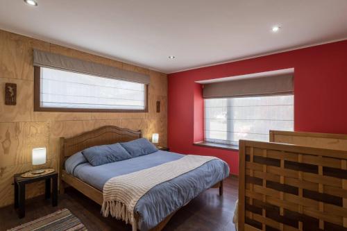 a bedroom with red walls and a bed and two windows at Cabañas Torre Huillinco in Huillinco
