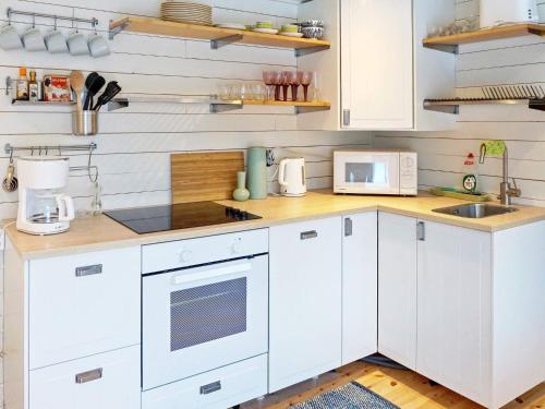 uma cozinha branca com armários brancos e um lavatório em 4 person holiday home in GRISSLEHAMN em Grisslehamn