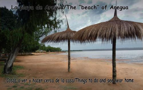 a beach with two straw umbrellas on the beach at Casa Charlie in Areguá