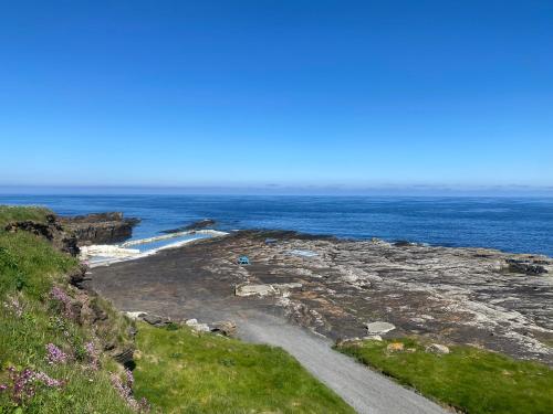 a dirt road next to the ocean on a cliff at Farr North Lodge 2 With Hot-Tub in Wick