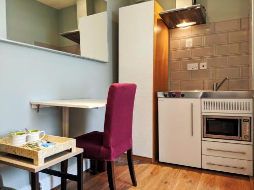 a small kitchen with a red chair and a table at Avis Hotel in Bromley