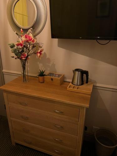 a dresser with a mirror and a vase of flowers on it at The Fox Inn in Abingdon