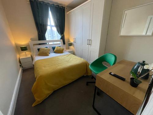 a bedroom with a bed with a yellow bedspread and a desk at Silver Eagle in Dublin