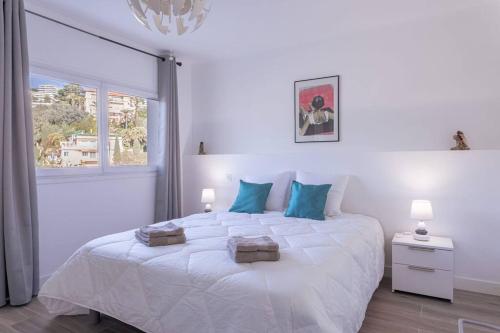 biała sypialnia z dużym białym łóżkiem z niebieskimi poduszkami w obiekcie Apartment With Panoramic Sea View, Walk To The Beach - Maréchal Juin by Halldis w Cannes