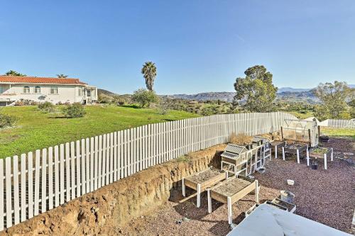 a fence with tables and chairs in front of a house at Fallbrook Home with Garden, Gazebo and Fire Pit! in Fallbrook