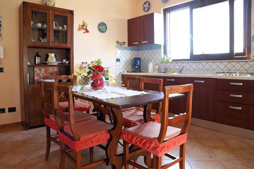 une cuisine avec une table en bois, des chaises et un îlot de cuisine dans l'établissement Lucy's cottage, à Cinisi