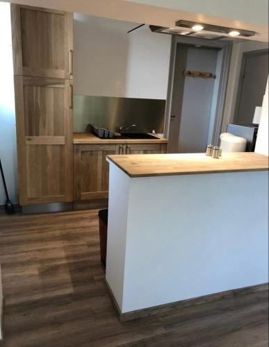 cocina con encimera blanca y armarios de madera en Résidence Harmonie Appartement N 4 meublé Avec Petit Déjeuner, en Néris-les-Bains