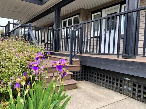 a house with stairs and purple flowers in front of it at Lovely J Home -Stunning river view cozy two bedroom private suite in New Westminster