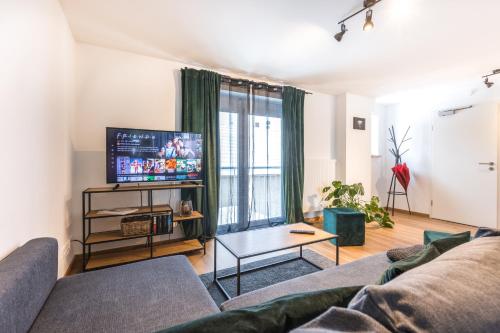 a living room with a couch and a flat screen tv at Arbio I Cozy Apartments Augsburg-Lechhausen in Augsburg