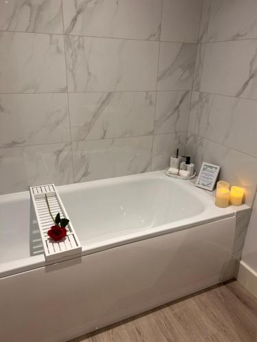 a white bath tub in a bathroom with marble walls at The Bay house Apartments , shanklin in Shanklin